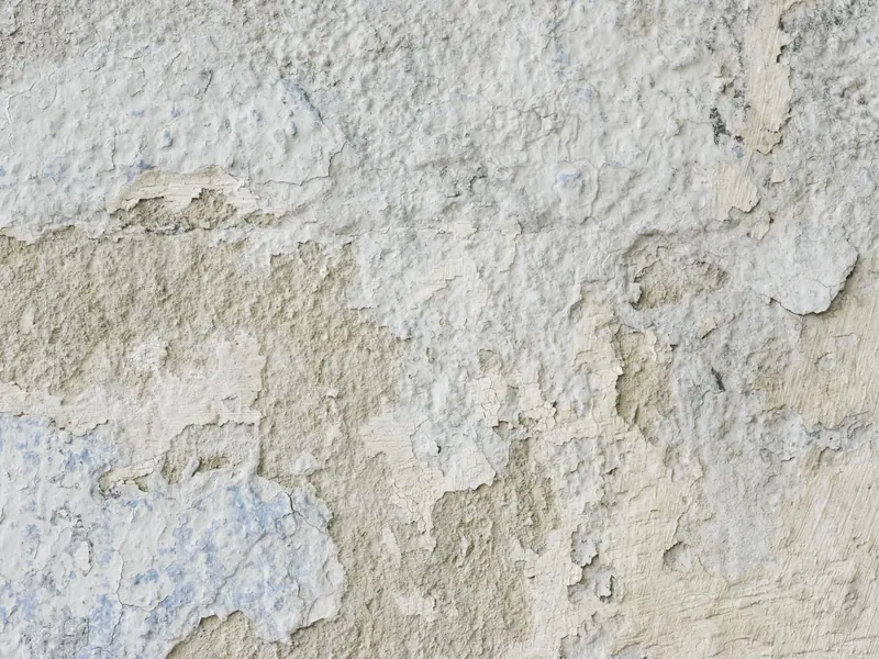 Peeling and spalling stucco showing finish failure on an older wall
