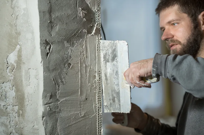 Plaster bedded over a perforated corner bead at an interior outside corner