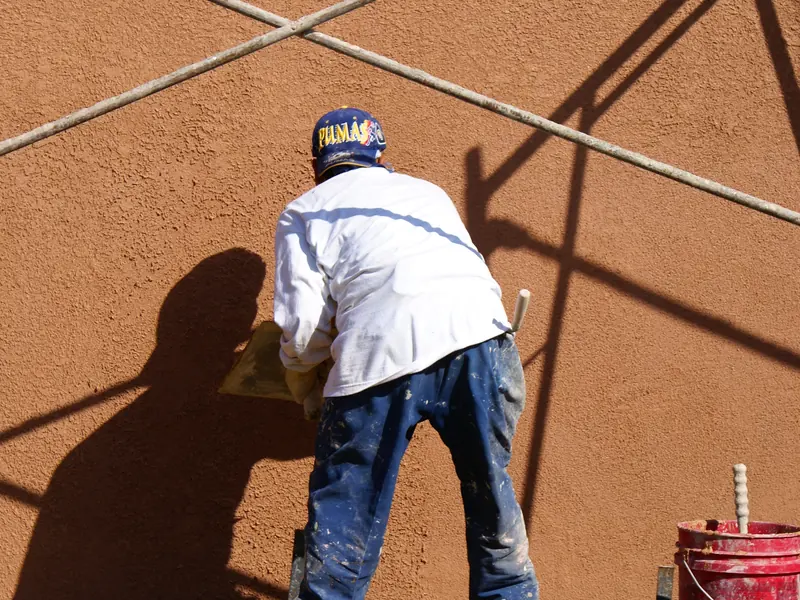 Stucco contractor applying a terracotta finish coat to a St. George home exterior